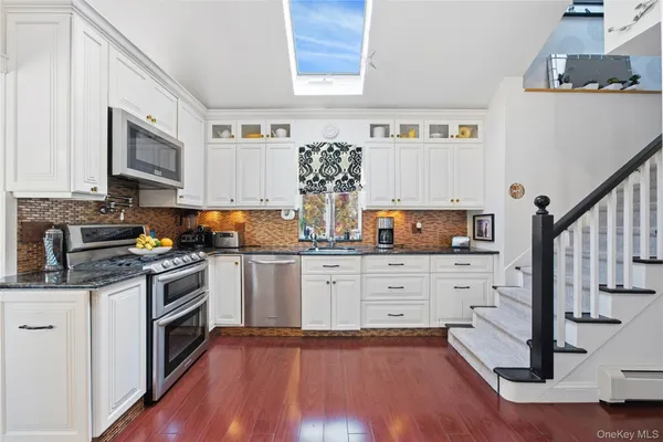 a kitchen with granite countertop a stove top oven microwave and cabinets