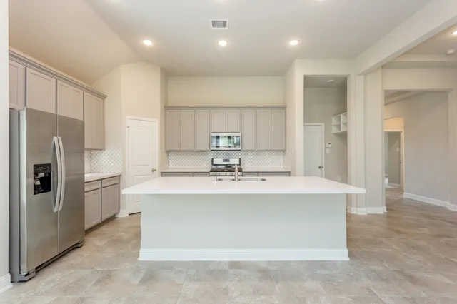 a kitchen with kitchen island a sink stainless steel appliances and cabinets