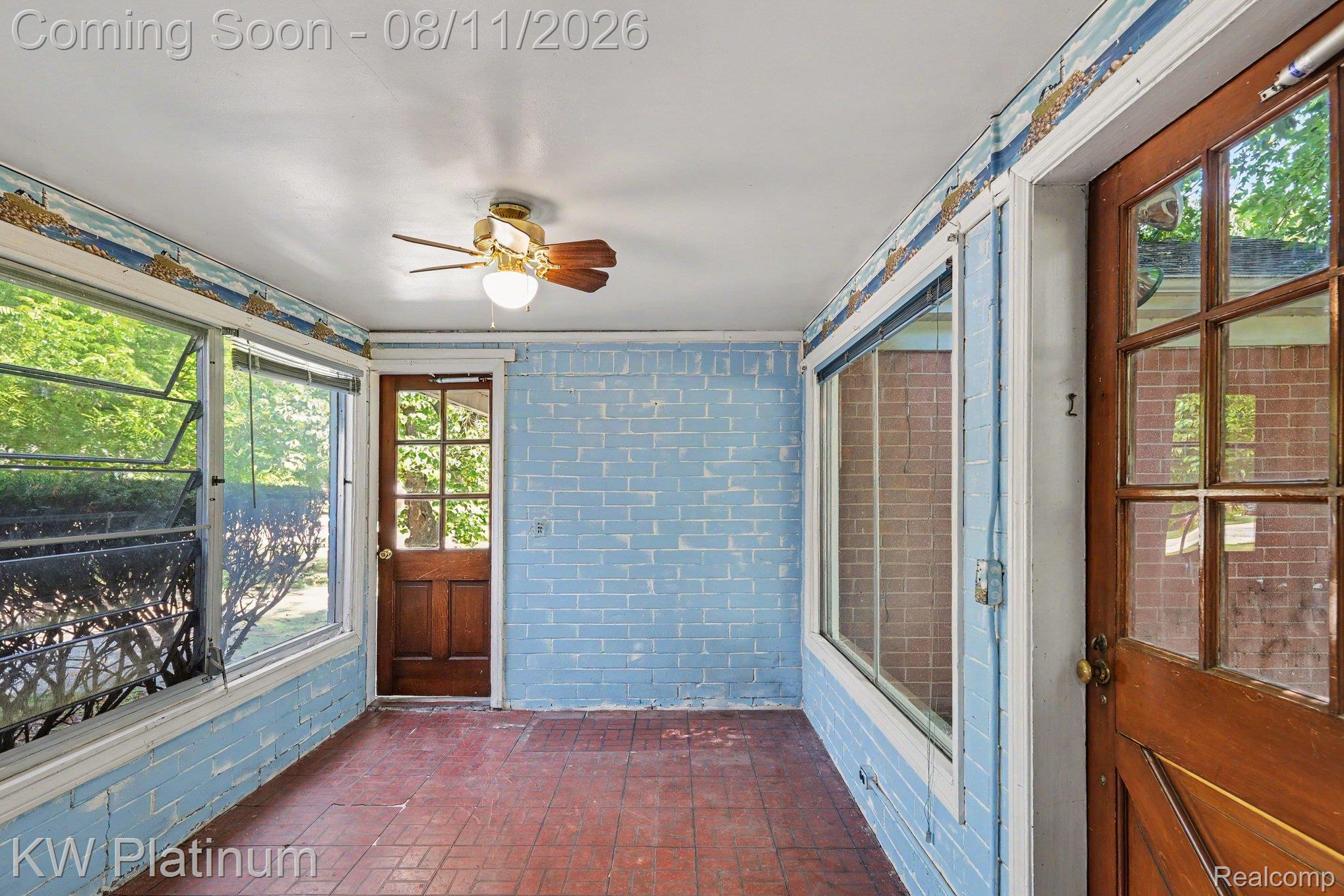 33200 Edgegrove Road Fraser, MI 48026 - Photo 19 of 23 Light blue brick walls, red tile flooring, multiple windows, two paneled wood doors, and a ceiling fan with integrated lighting