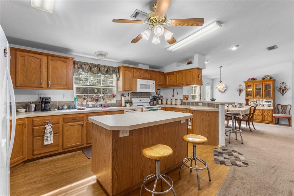 12251 Southeast 66th Place Morriston, FL 32668 - Photo 46 of 55 a kitchen with stainless steel appliances granite countertop a stove top oven a sink a dining table and chairs with wooden floor