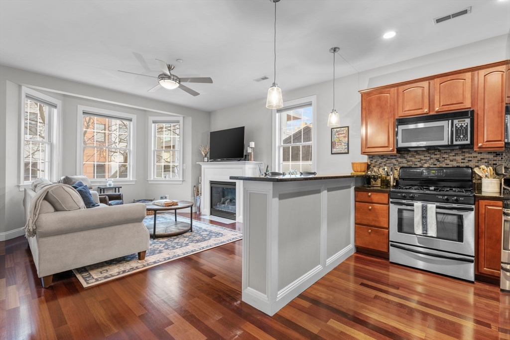34 H Street, Unit 2L Boston, MA 02127 - Photo 3 of 20 a kitchen with stainless steel appliances granite countertop a stove top oven a sink dishwasher a dining table and chairs with wooden floor