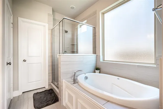 a bathroom with a tub a window and a shower