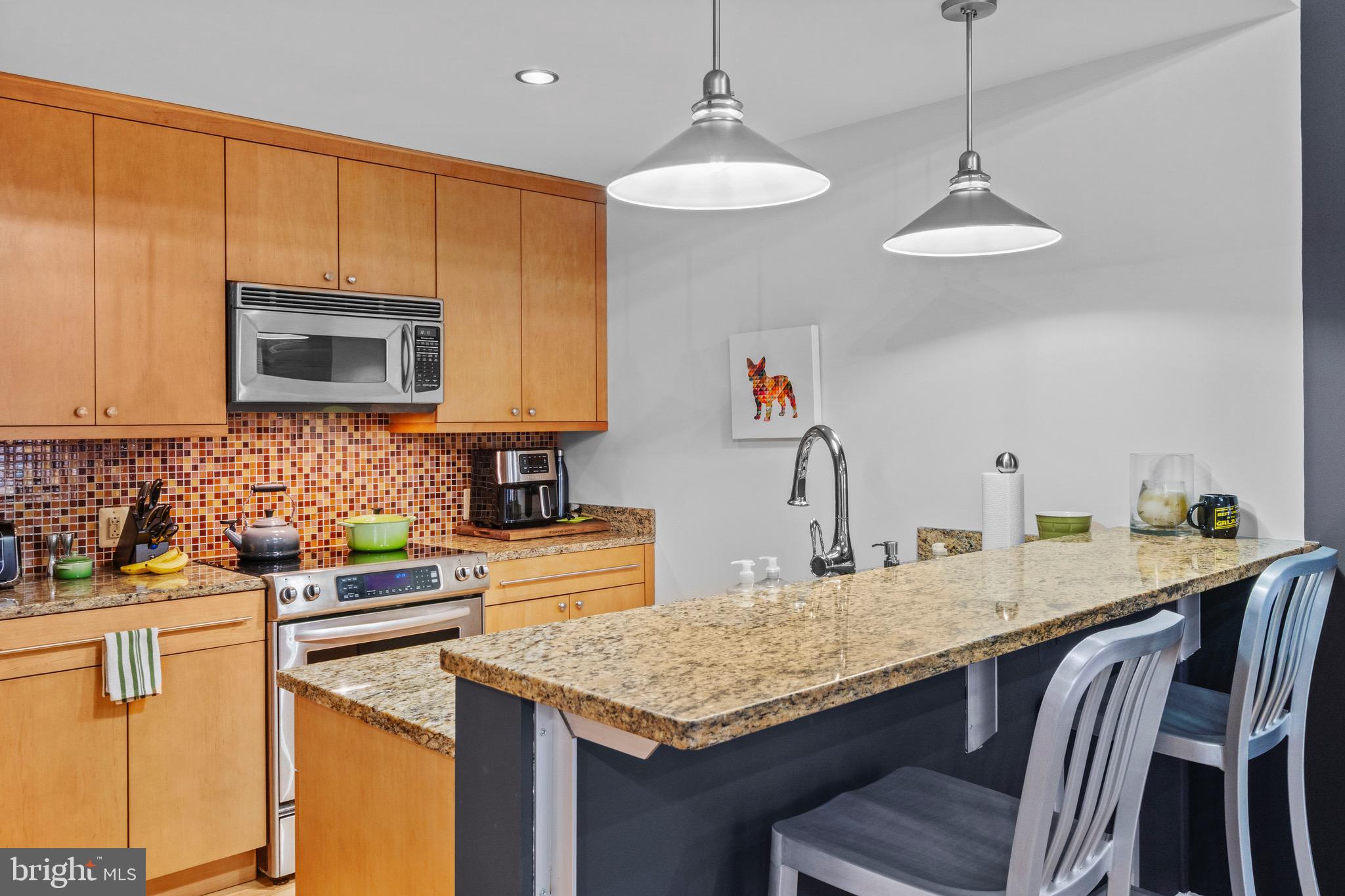 850 Aliceanna Street, Unit 604 Baltimore, MD 21202 - Photo 12 of 43 a kitchen with stainless steel appliances granite countertop a kitchen island a stove a sink a dining table and chairs