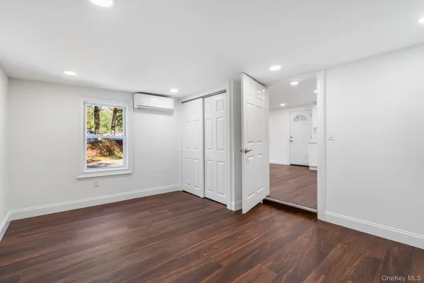 a view of an empty room with wooden floor and window