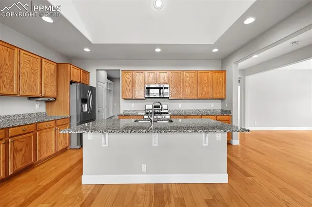 a view of a kitchen with stainless steel appliances granite countertop a stove a sink and a refrigerator