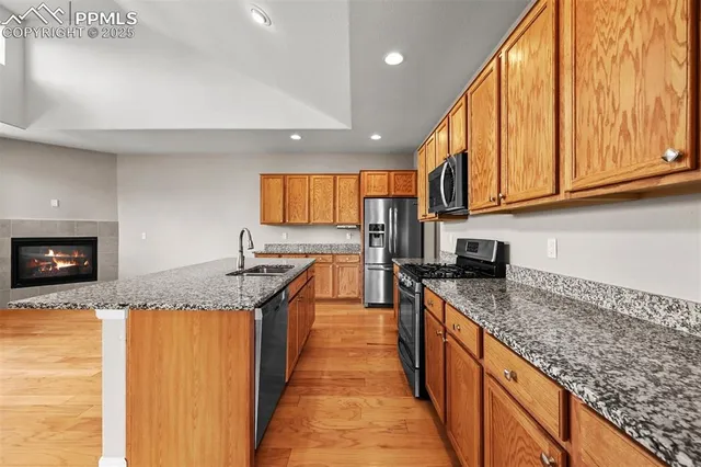 a kitchen with granite countertop stainless steel appliances a sink a counter top space and cabinets