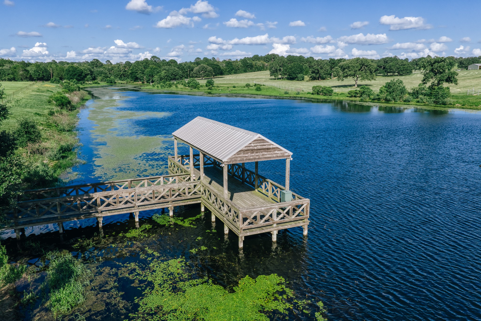 1034 Hilbun Road New Ulm, TX 78950 - Photo 38 of 49 A covered dock extends into the stocked 7-acre lake, complete with electricity and panoramic water views—perfect for fishing, entertaining, or simply enjoying the peaceful surroundings.