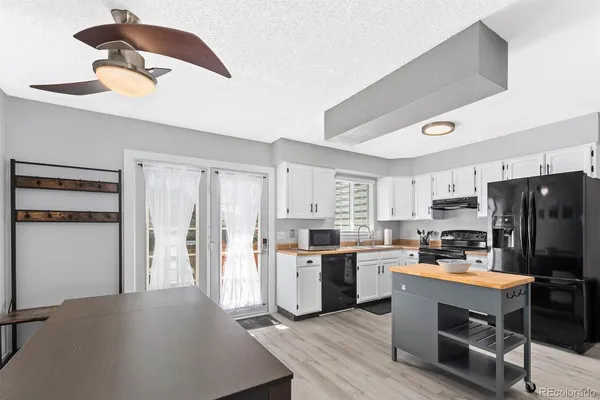 a kitchen with stainless steel appliances a refrigerator a stove a sink dishwasher and white cabinets with wooden floor