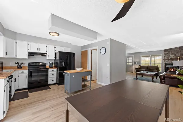 a kitchen with stainless steel appliances kitchen island granite countertop a refrigerator a stove top oven a sink dishwasher and wooden cabinets with wooden floor