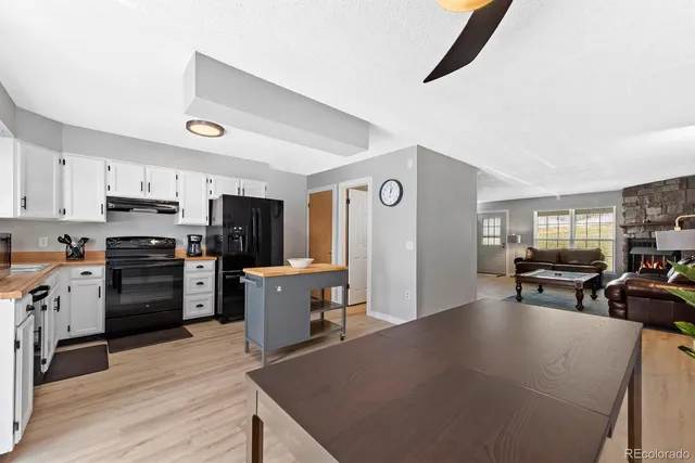 a kitchen with stainless steel appliances kitchen island granite countertop a refrigerator a stove top oven a sink dishwasher and wooden cabinets with wooden floor