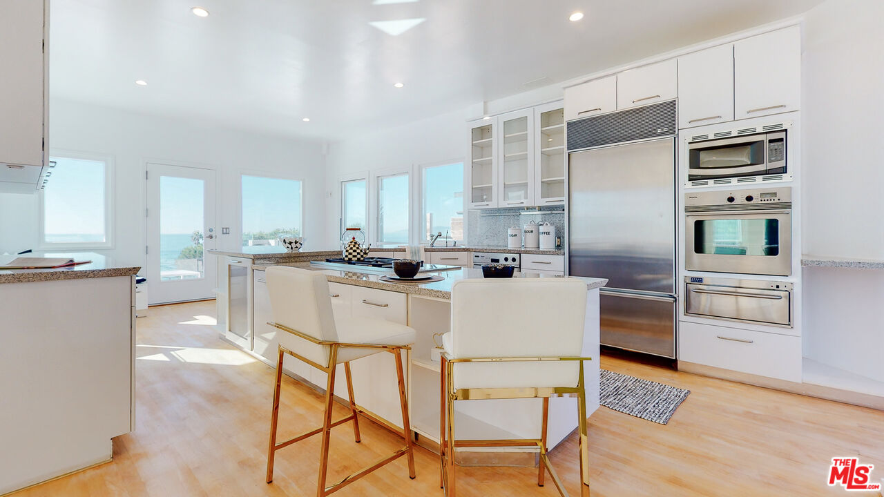 201 Waterview Street Playa del Rey, CA 90293 - Photo 21 of 54 a kitchen with stainless steel appliances kitchen island granite countertop a refrigerator a stove a sink and white cabinets with wooden floor