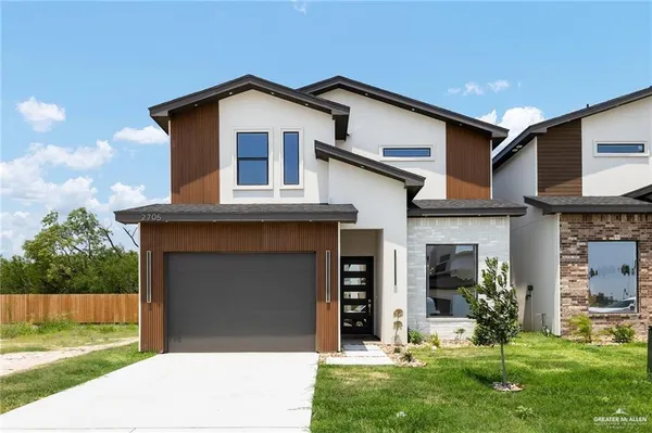 a front view of a house with a yard and trees