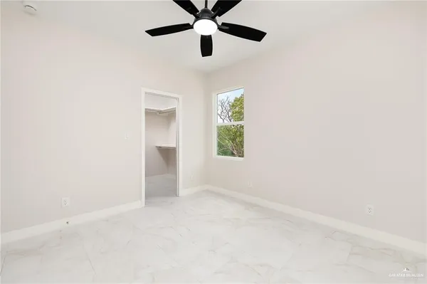 an empty room with windows and fan