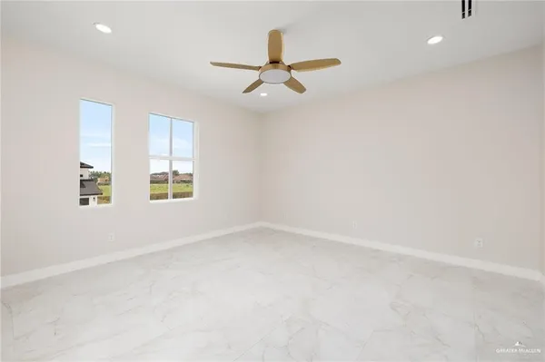 an empty room with windows and ceiling fan