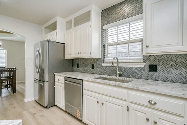 a kitchen with granite countertop a sink cabinets and stainless steel appliances