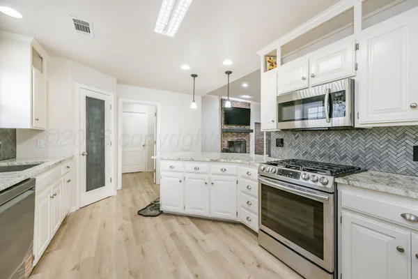 a kitchen with stainless steel appliances white cabinets and stove top oven