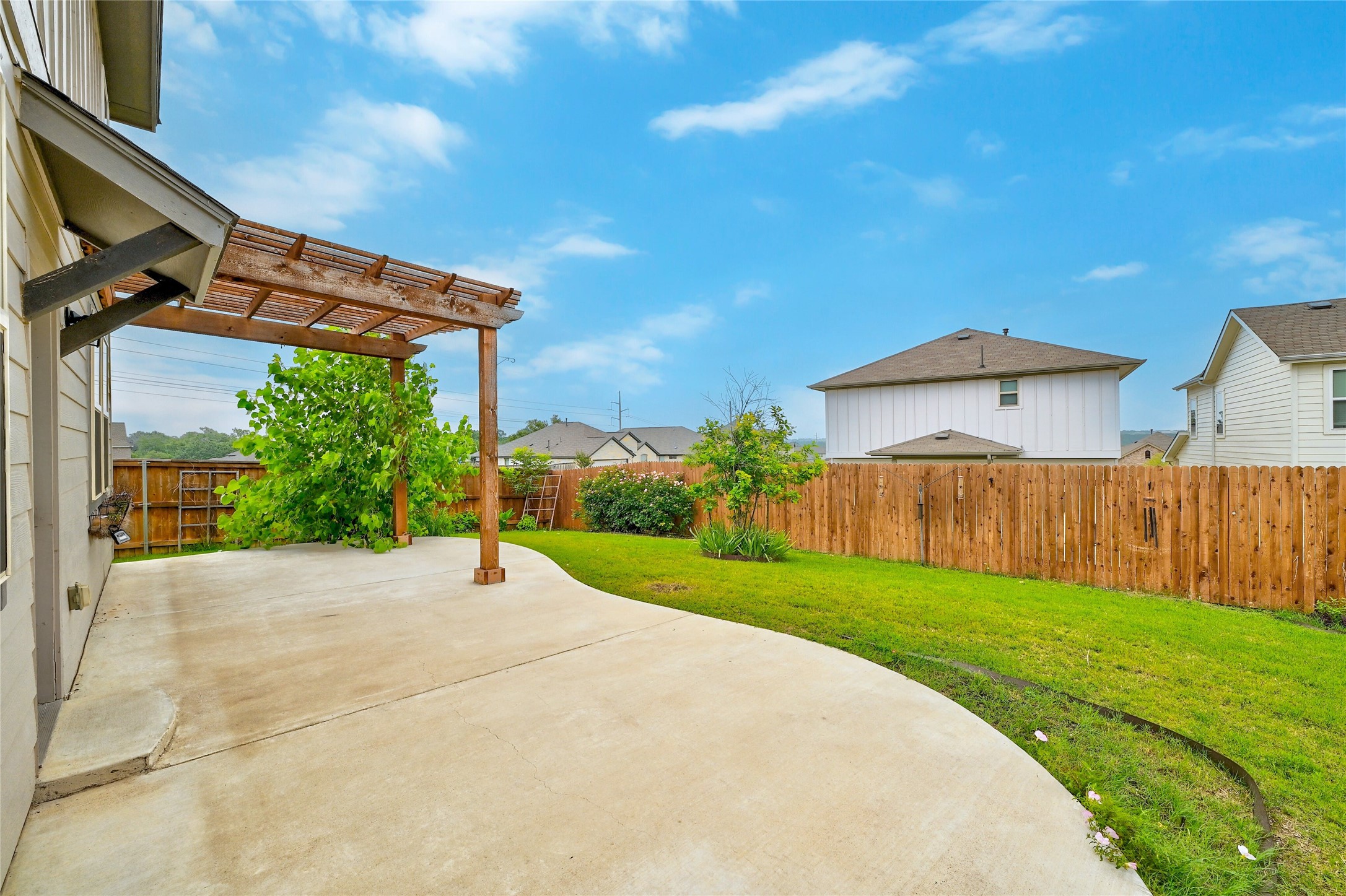 101 Lambert Street Leander, TX 78641 - Photo 31 of 33 An inviting backyard features a wooden pergola and a freshly manicured lawn.