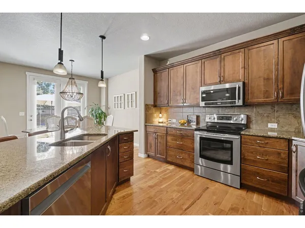 a kitchen with kitchen island granite countertop a sink stainless steel appliances and cabinets