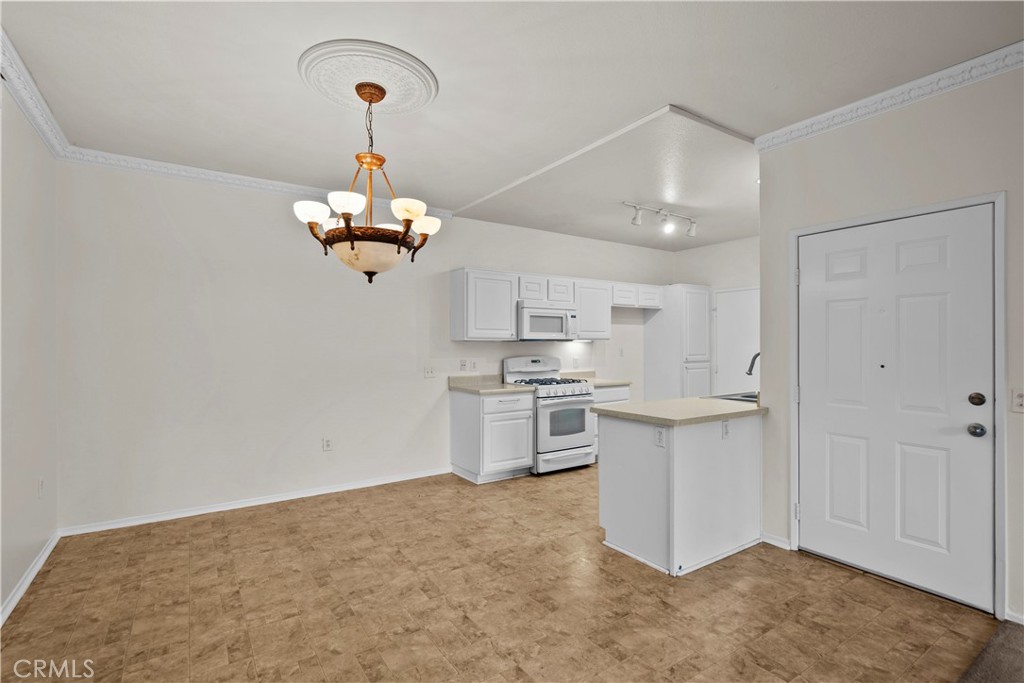 20000 Plum Canyon Road, Unit 1316 Saugus, CA 91350 - Photo 9 of 37 a kitchen with kitchen island white cabinets stainless steel appliances and a chandelier