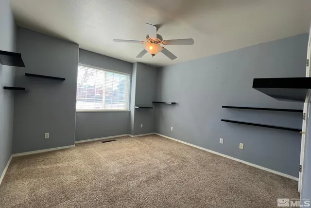 an empty room with windows and fan