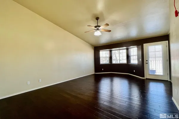 a view of an empty room with a window and wooden floor
