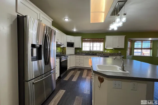 a kitchen with stainless steel appliances granite countertop a refrigerator a sink dishwasher a stove and a sink with wooden floor