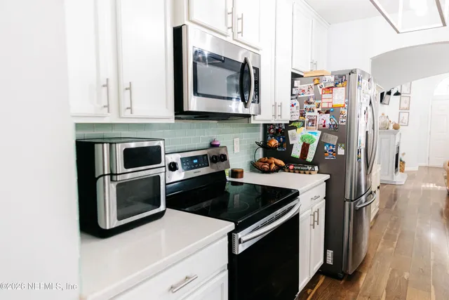 a kitchen with stainless steel appliances white cabinets and a stove top oven