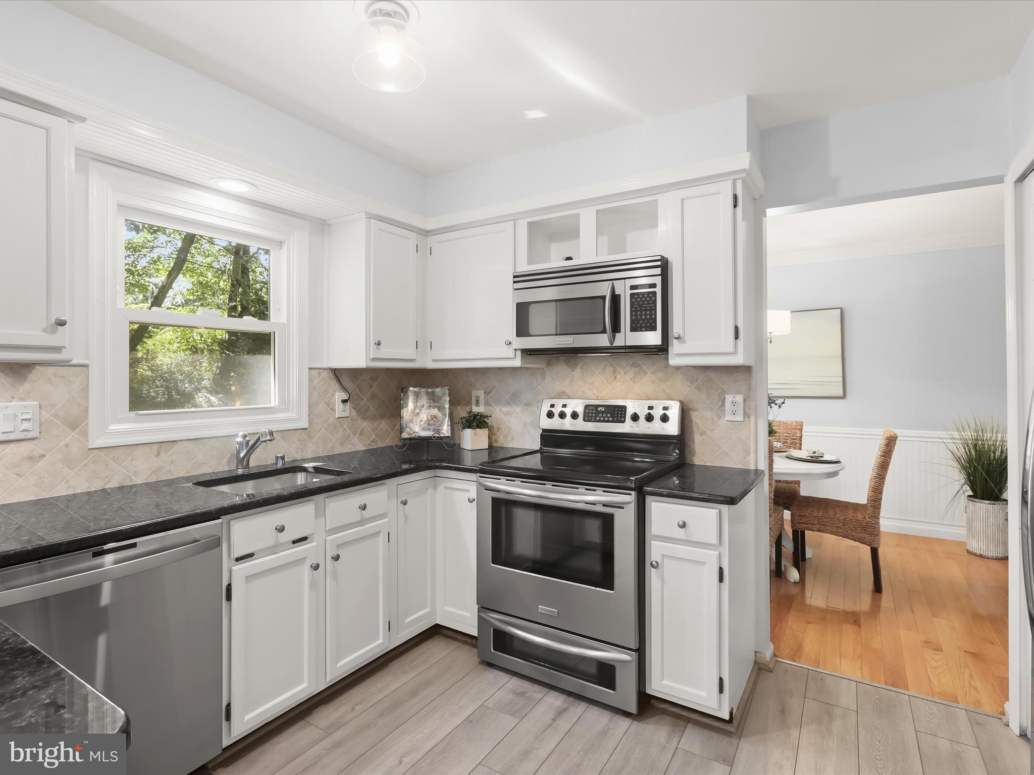 303 Riding Ridge Road Annapolis, MD 21403 - Photo 14 of 43 a kitchen with stainless steel appliances granite countertop a stove a sink a microwave a window and white cabinets