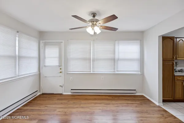an empty room with wooden floor closet and windows