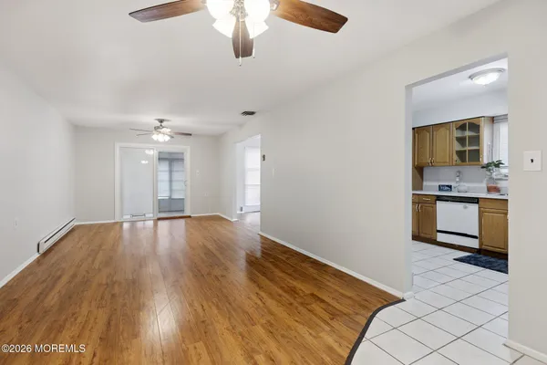 a view of kitchen and empty room with wooden floor