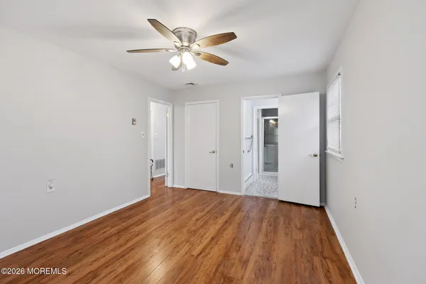 a view of a big room with wooden floor and a chandelier fan