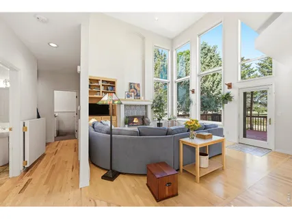 a living room with furniture a large window and wooden floor
