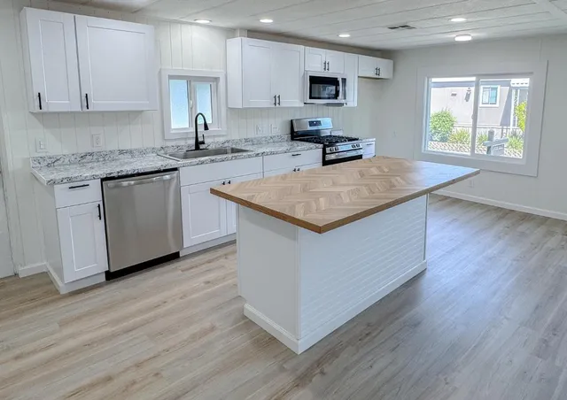 a kitchen with stainless steel appliances granite countertop a stove a sink and a microwave