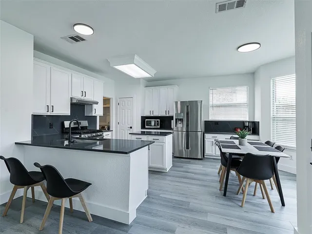 a kitchen with stainless steel appliances kitchen island granite countertop a table chairs microwave and sink