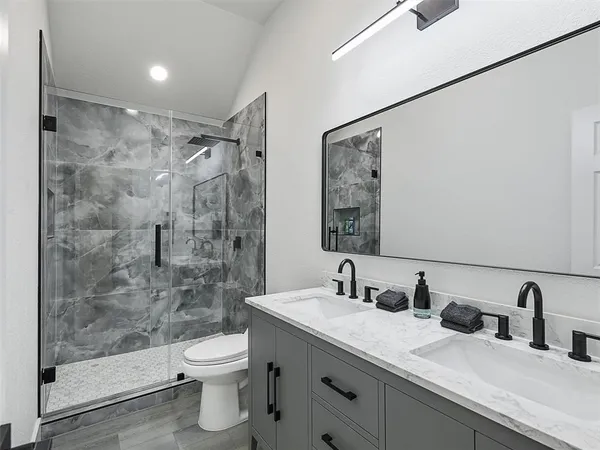a bathroom with a double vanity sink toilet and shower