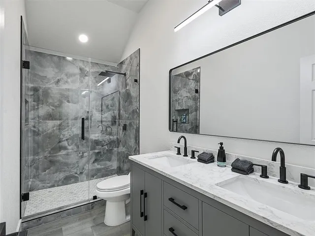 a bathroom with a double vanity sink toilet and shower