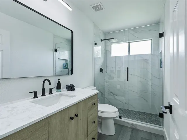 a bathroom with a sink a toilet and shower