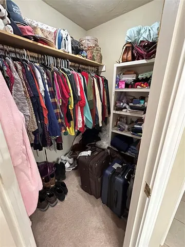 a view of walk in closet with clothes and shoes