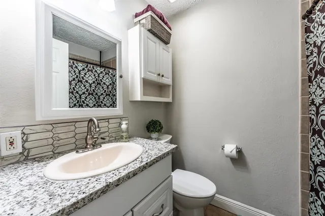 a bathroom with a granite countertop sink toilet and mirror