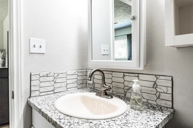 a bathroom with a granite countertop sink and a mirror
