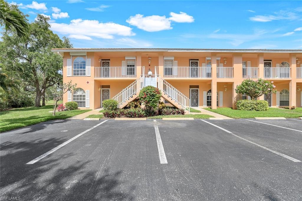 View of building exterior featuring uncovered parking and stairway