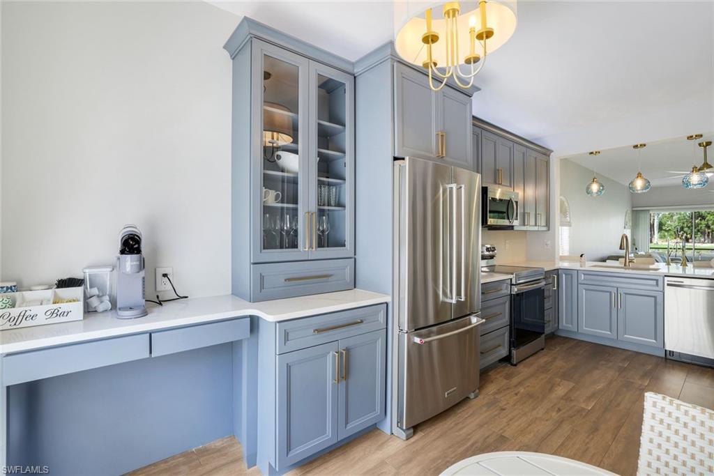 555 Augusta Boulevard, Unit 31 Naples, FL 34113 - Photo 7 of 17 Kitchen featuring gray cabinets, a sink, appliances with stainless steel finishes, glass insert cabinets, and wood finished floors