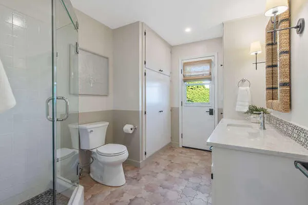 a bathroom with a granite countertop toilet a sink a mirror and a window