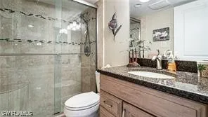 a bathroom with a granite countertop sink a toilet and shower