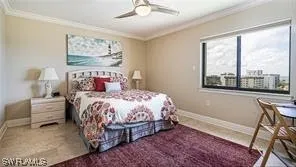 a bedroom with a bed painting on wall and a large window