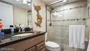 a bathroom with a granite countertop sink a toilet and shower