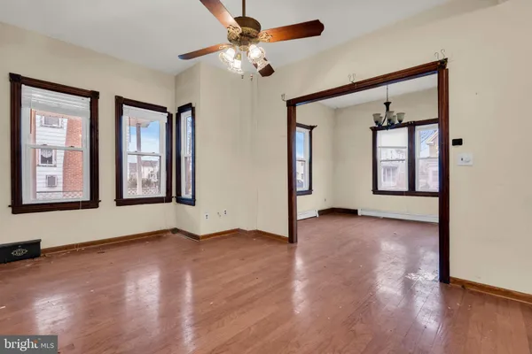 an empty room with wooden floor chandelier and windows