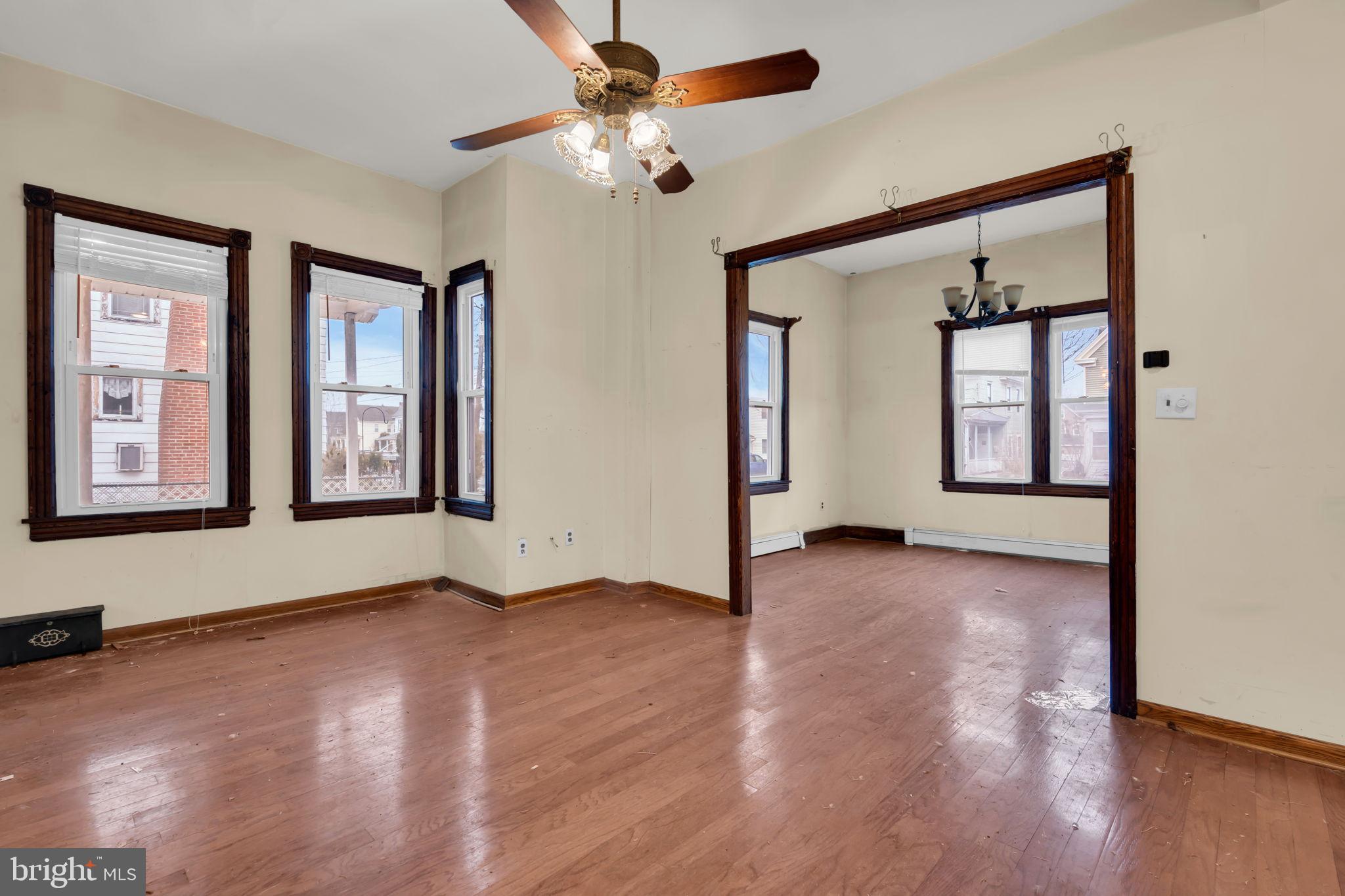104 Maple Street Clayton, NJ 08312 - Photo 4 of 13 an empty room with wooden floor chandelier and windows