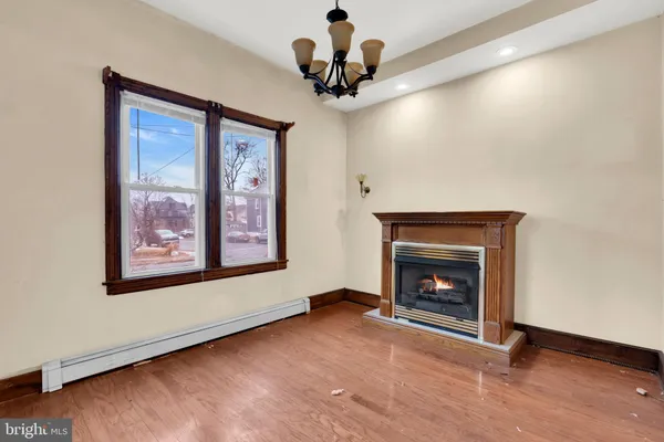 a view of an empty room with wooden floor fireplace and a window