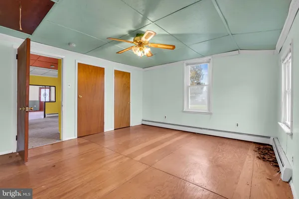 an empty room with wooden floor chandelier and windows
